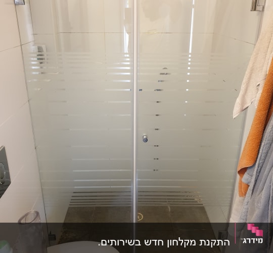 מקלחון זכוכית עם דלתות שקופות ותליית מגבות